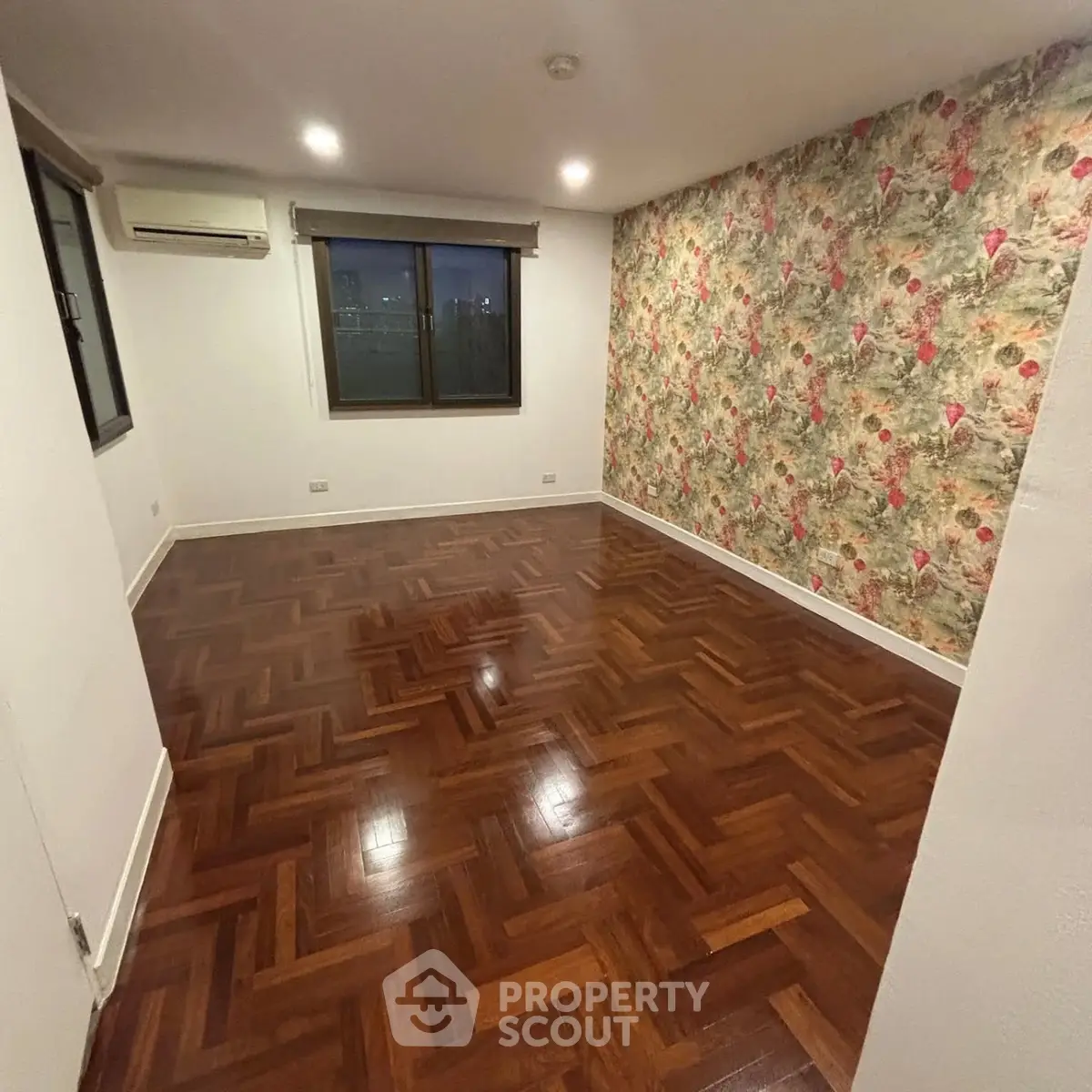 Spacious room with elegant wooden flooring and floral accent wall, perfect for customization.