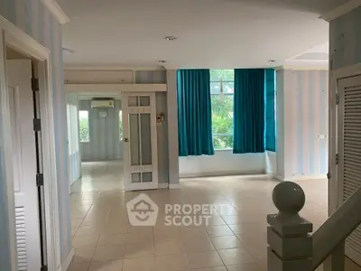 Spacious living area with large windows and blue curtains, ideal for natural light lovers.