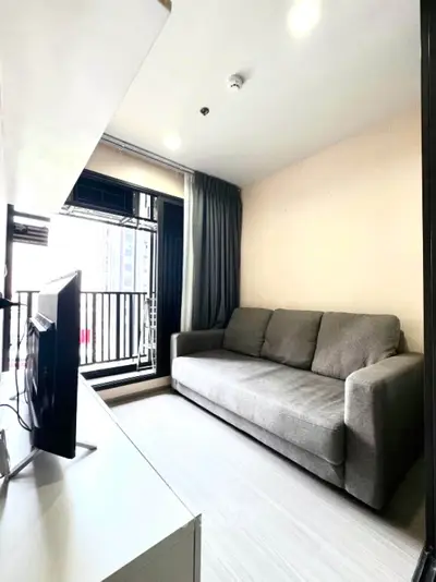 Modern living room with cozy gray sofa and balcony view in urban apartment.