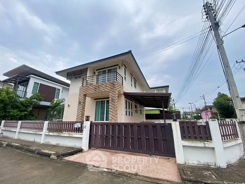 Modern two-story house with spacious balcony and gated entrance in suburban neighborhood.