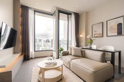 Modern living room with large windows and city view, featuring elegant decor and comfortable seating.