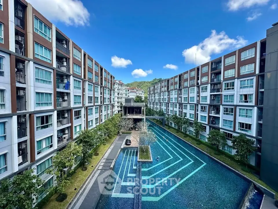 Luxurious apartment complex with stunning pool and modern architecture under a clear blue sky.