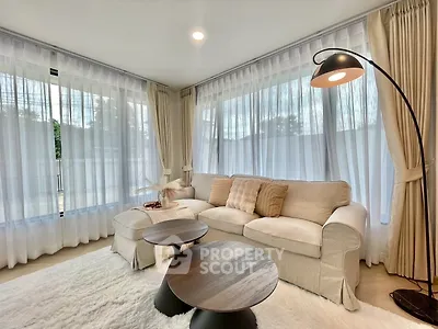 Elegant living room with cozy sofa, modern floor lamp, and large windows with sheer curtains.