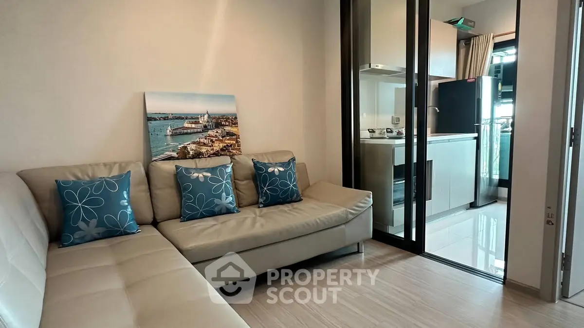 Modern living room with sleek kitchen, featuring a cozy sofa and stylish decor in a contemporary apartment.