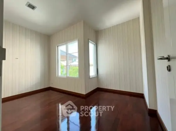 Spacious empty room with polished wooden floors and large windows