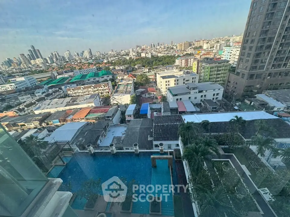 Stunning cityscape view from high-rise building with pool and urban skyline.