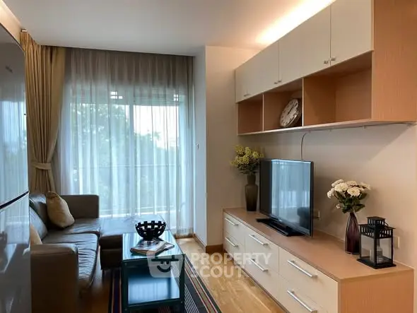 Modern living room with sleek furniture and large window offering natural light.