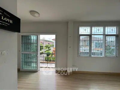 Bright living room with large windows and balcony access, offering a serene view.