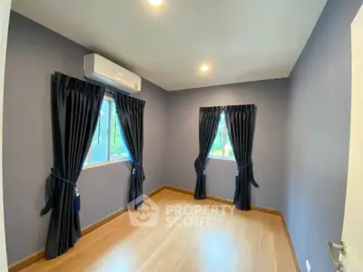 Spacious empty room with wooden flooring and large windows, perfect for customization.