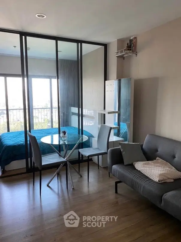 Modern studio apartment with glass partition, cozy living area, and stylish dining set.