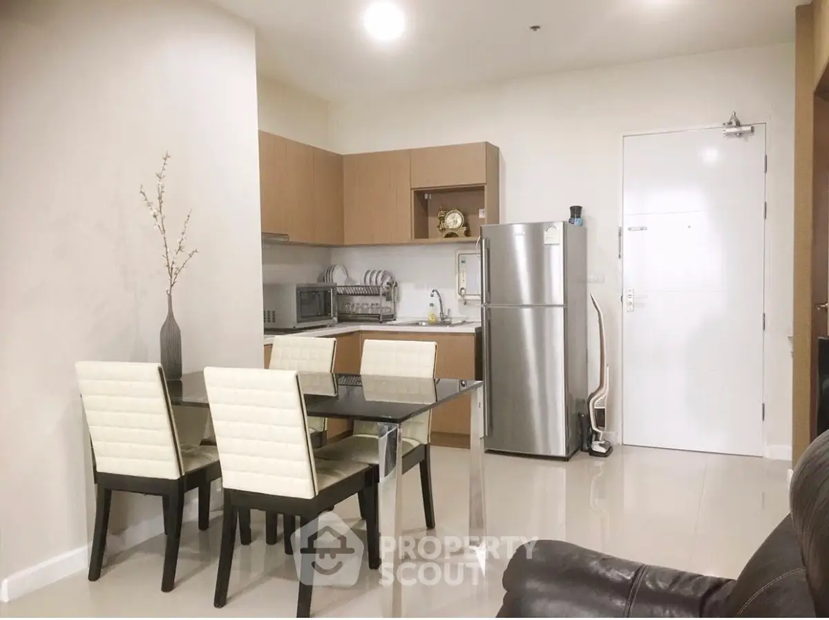 Modern kitchen with dining area and stainless steel appliances in cozy apartment.
