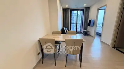 Modern dining area with elegant table and chairs, open layout leading to a cozy living space with city view.