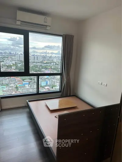 Modern bedroom with stunning city view and large window, featuring sleek wooden flooring and minimalist design.