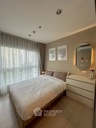 Cozy modern bedroom with large window and stylish decor in urban apartment.