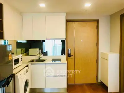 Modern compact kitchen with washing machine and sleek appliances in cozy apartment.