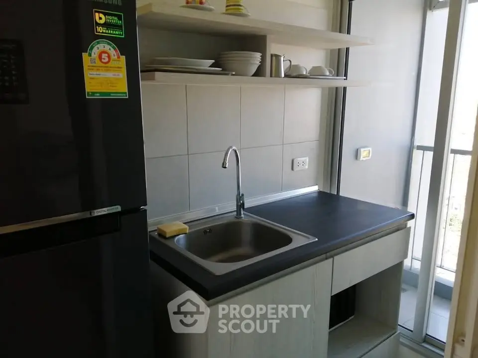 Modern kitchen with sleek design and balcony view, featuring a compact layout and stylish appliances.