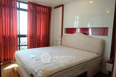 Spacious bedroom with large window and elegant red curtains, featuring a comfortable bed and ample storage.