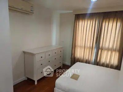 Cozy bedroom with natural light, featuring a white dresser and air conditioning for comfort.