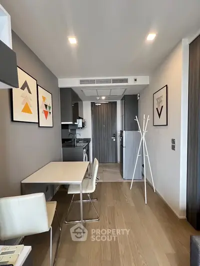 Modern apartment interior with stylish kitchen and dining area, featuring contemporary artwork and sleek furniture.