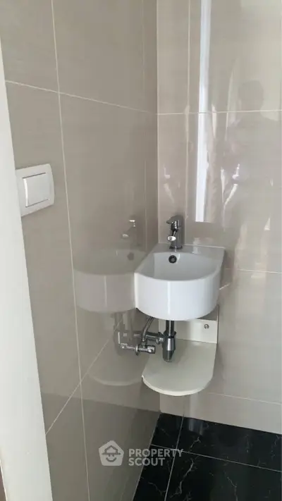 Compact modern bathroom with sleek white sink and glossy tiles