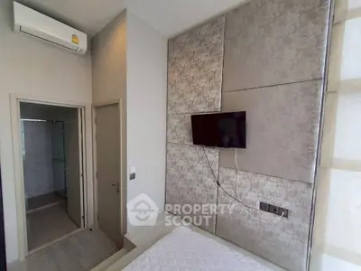 Modern bedroom with wall-mounted TV and air conditioning, featuring a sleek design and neutral tones.