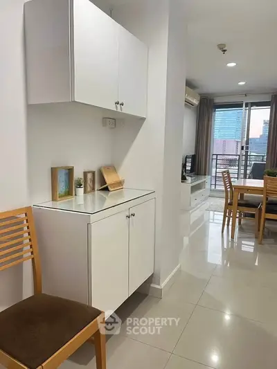 Modern apartment interior with sleek white cabinets and open living area, featuring a city view balcony.