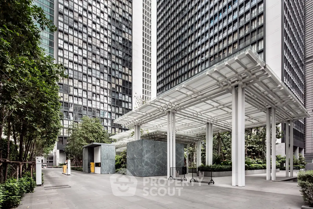 Modern high-rise building entrance with sleek design and lush greenery