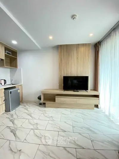 Modern living room with sleek kitchen, stylish TV unit, and elegant tile flooring.