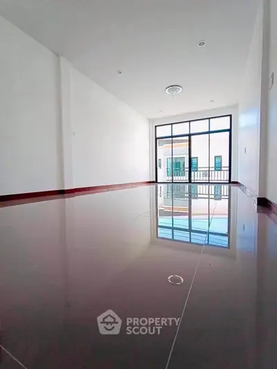Spacious empty room with large window and glossy floor, perfect for customization.