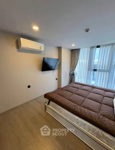 Modern bedroom with wall-mounted TV and air conditioning in a bright apartment.