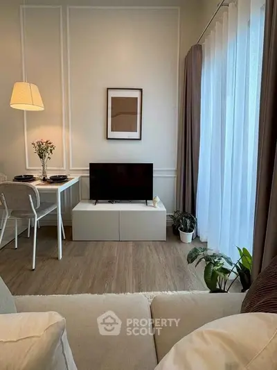 Cozy living room with modern decor, featuring a small dining area and natural light from large windows.