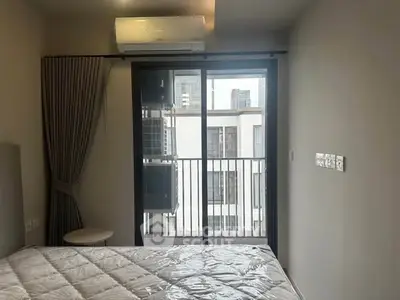 Modern bedroom with balcony access and city view, featuring air conditioning and minimalist decor.