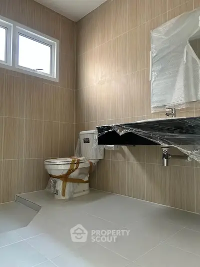 Modern bathroom with sleek fixtures and natural light, featuring a stylish wall-mounted sink and contemporary toilet.