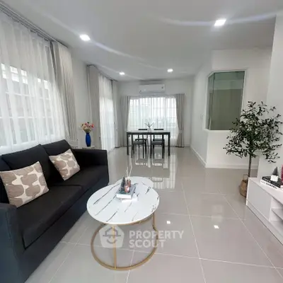 Modern living room with sleek furniture and large windows in a bright, open space.