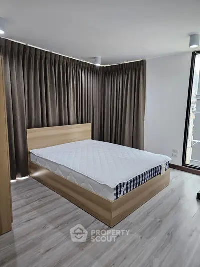 Spacious bedroom with modern wooden bed and floor-to-ceiling curtains
