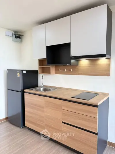 Modern kitchen with sleek cabinets and compact fridge in a stylish apartment.