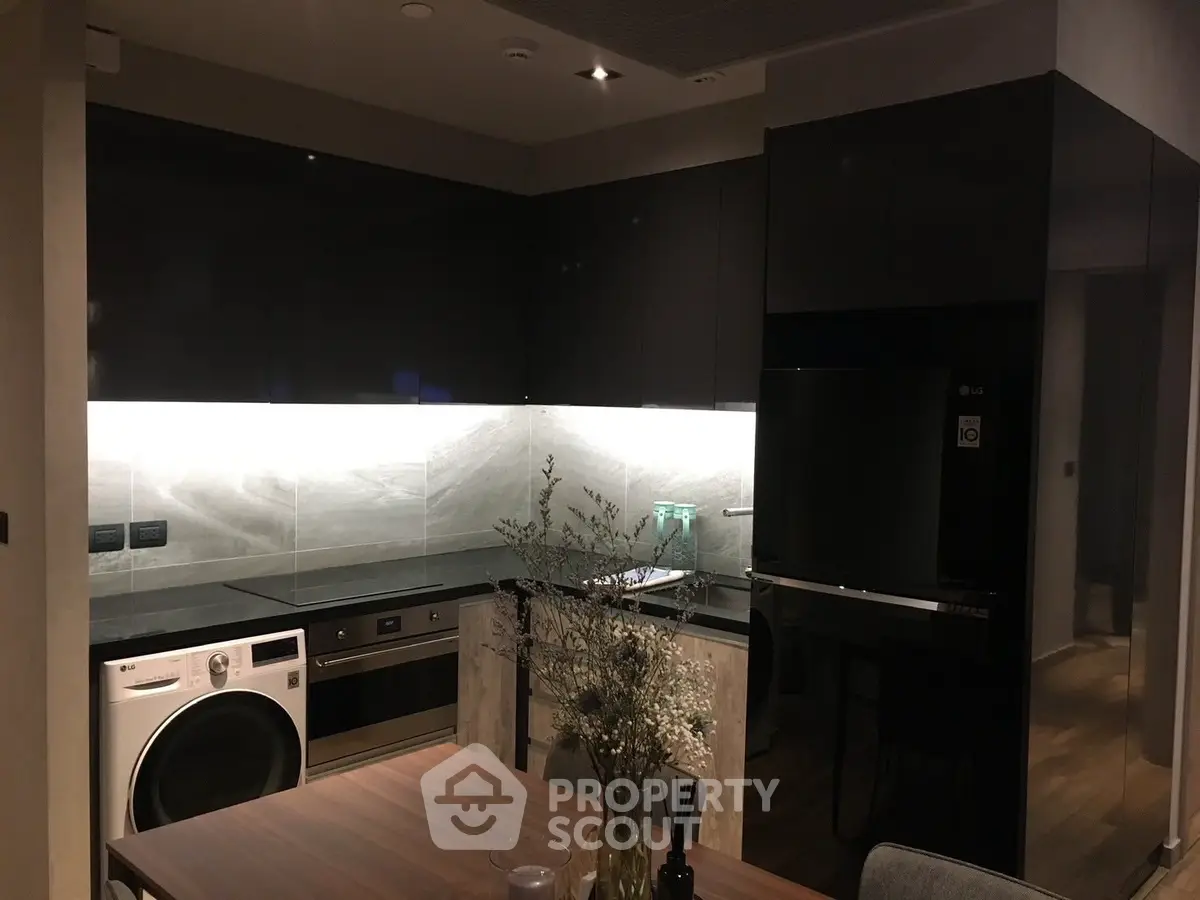 Modern kitchen with sleek black cabinets, integrated appliances, and stylish lighting.