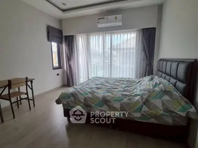 Spacious bedroom with modern decor and large windows for natural light