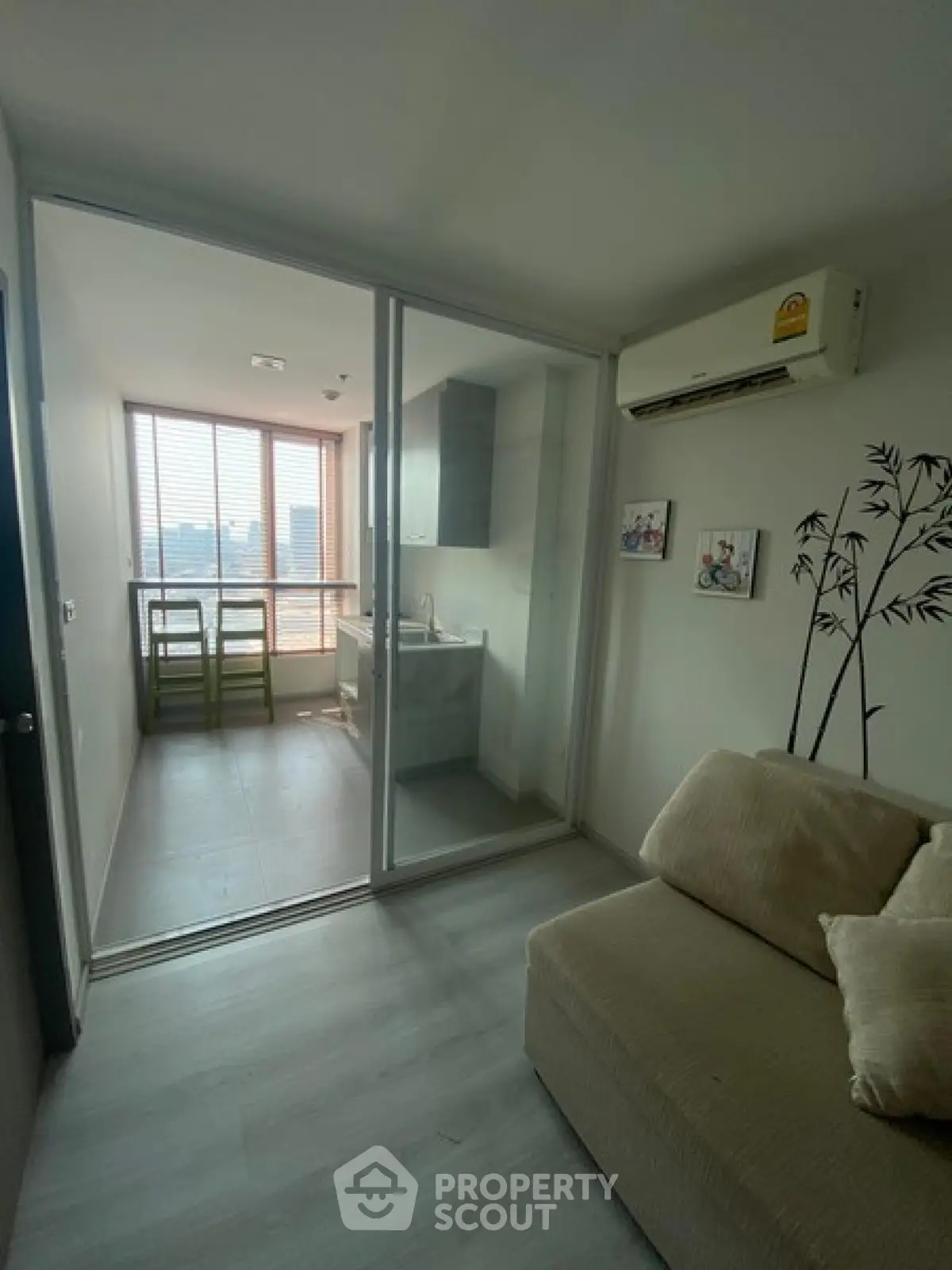 Cozy living room with sliding glass doors leading to a compact kitchen, featuring modern decor and city views.
