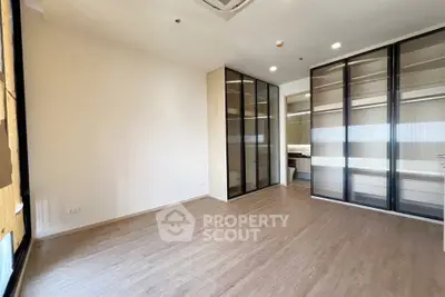 Spacious modern bedroom with sleek glass wardrobes and wooden flooring