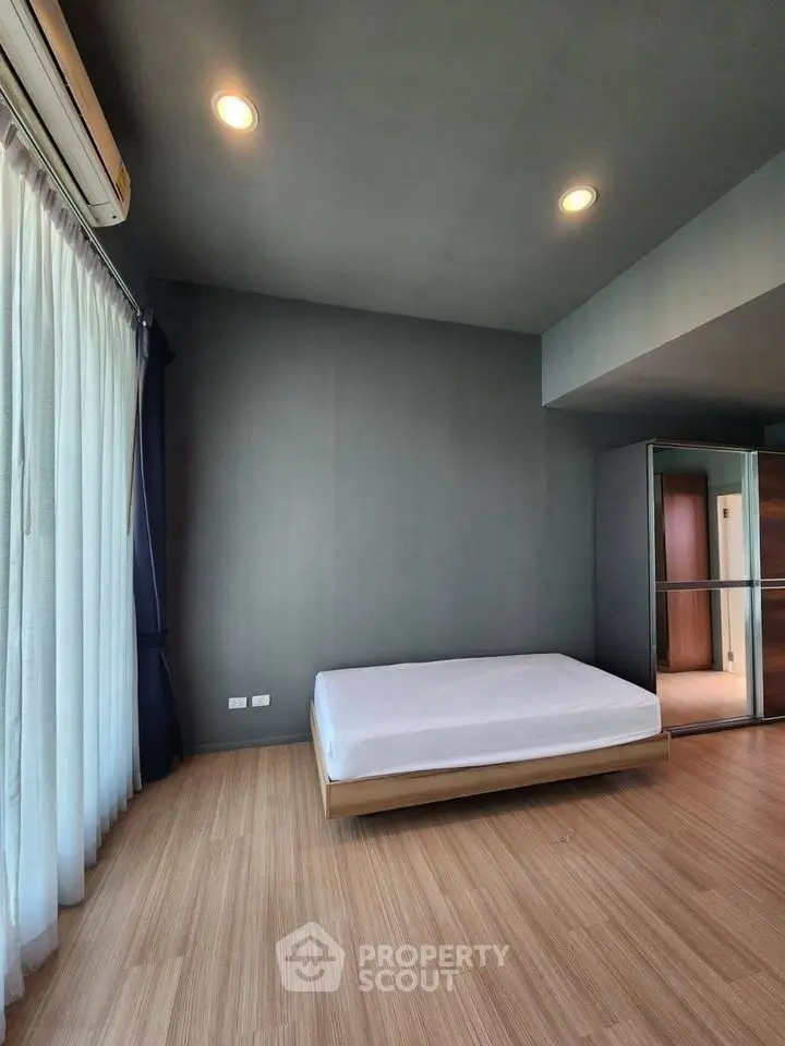 Spacious bedroom with minimalist design and large window for natural light.
