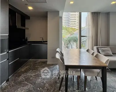 Modern open-plan living and dining area with sleek kitchen and large windows.