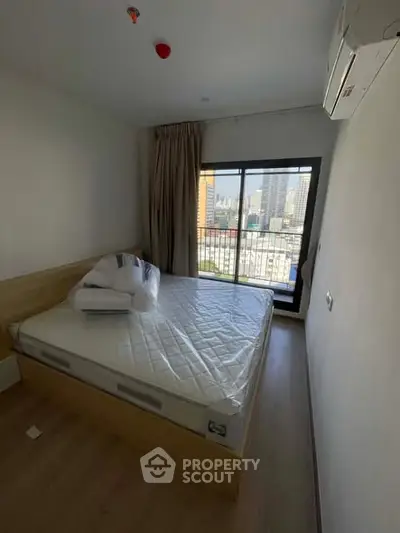 Modern bedroom with city view and large window, featuring a comfortable bed and air conditioning.