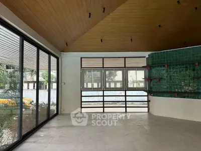 Spacious modern living room with large windows and stylish wooden ceiling