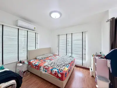 Bright and cozy bedroom with wooden flooring and ample natural light, featuring modern furnishings and air conditioning.