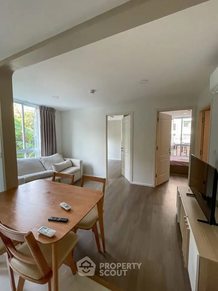 Modern living room with wooden flooring and natural light, featuring a cozy sofa and dining area.