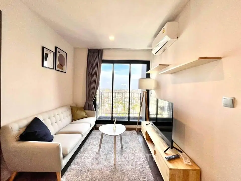Modern living room with cozy sofa, stylish decor, and large window offering city views.