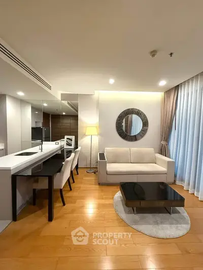 Modern living room with elegant decor, featuring a cozy sofa, stylish mirror, and open kitchen layout.