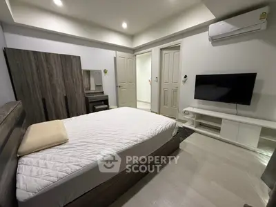 Modern bedroom with sleek furniture and wall-mounted TV in a stylish apartment.