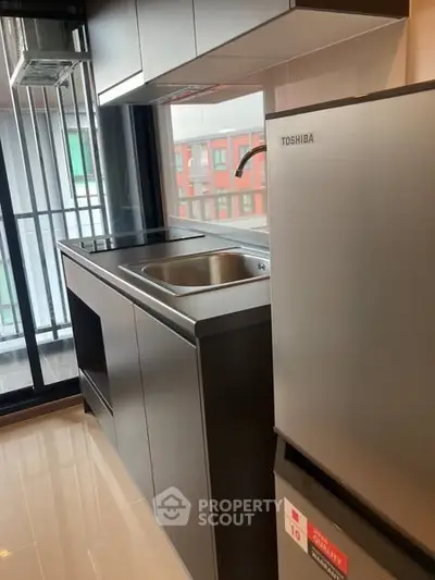 Modern kitchen with sleek cabinetry and stainless steel appliances in urban apartment.